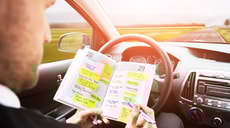 Autofahrer führt ein Fahrtenbuch per Stift am Steuer.